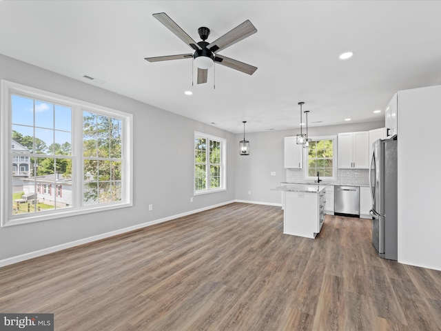 kitchen featuring white cabinetry, tasteful backsplash, a kitchen island, stainless steel appliances, and wood-type flooring