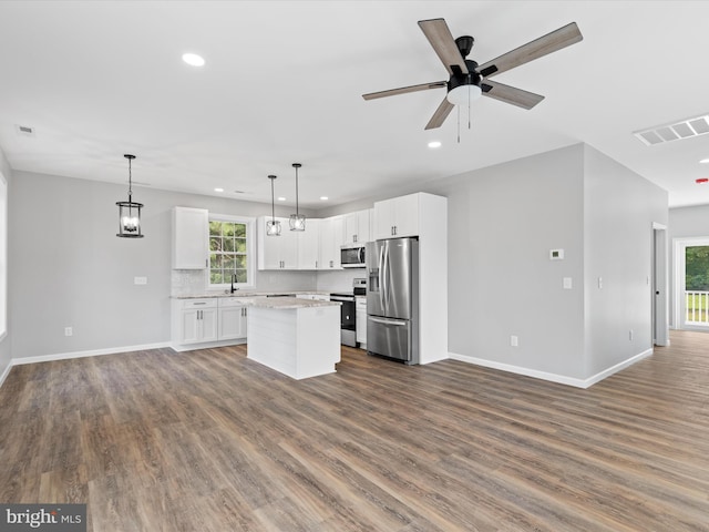 kitchen with hanging light fixtures, wood-type flooring, a kitchen island, and stainless steel appliances