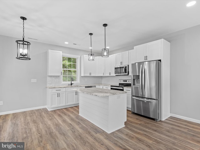 kitchen with decorative light fixtures, light hardwood / wood-style flooring, white cabinets, and stainless steel appliances