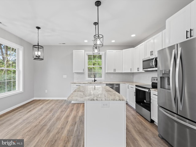 kitchen featuring a healthy amount of sunlight, appliances with stainless steel finishes, light stone counters, and light hardwood / wood-style floors