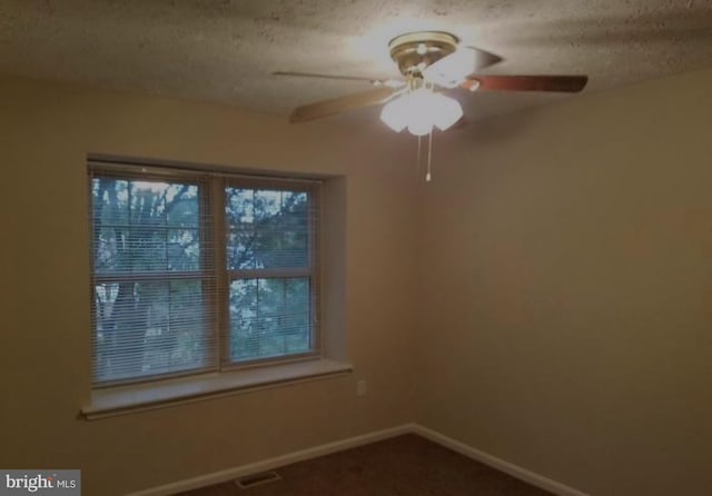 carpeted spare room featuring ceiling fan and a textured ceiling