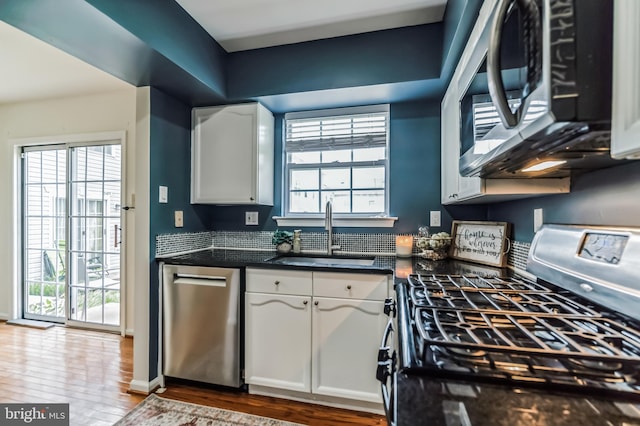 kitchen featuring hardwood / wood-style flooring, stainless steel appliances, a healthy amount of sunlight, white cabinets, and sink