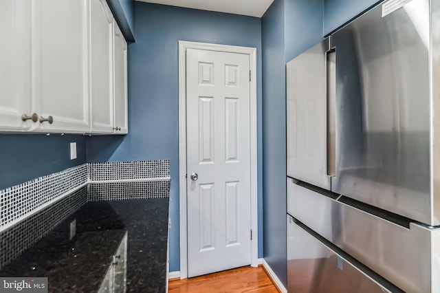 kitchen featuring high end fridge, dark stone counters, white cabinetry, and light wood-type flooring