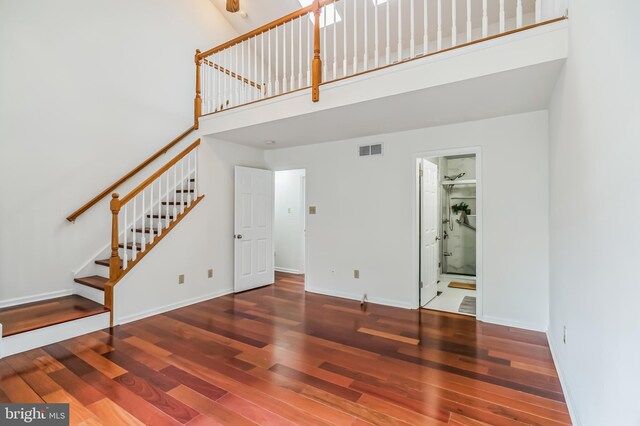 unfurnished living room with wood-type flooring and a towering ceiling