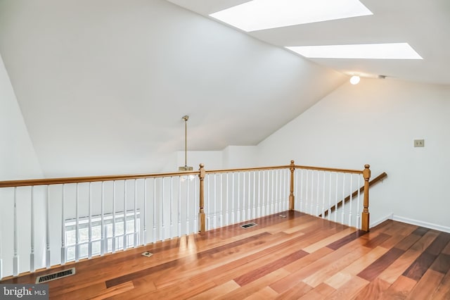 additional living space with lofted ceiling with skylight and hardwood / wood-style floors