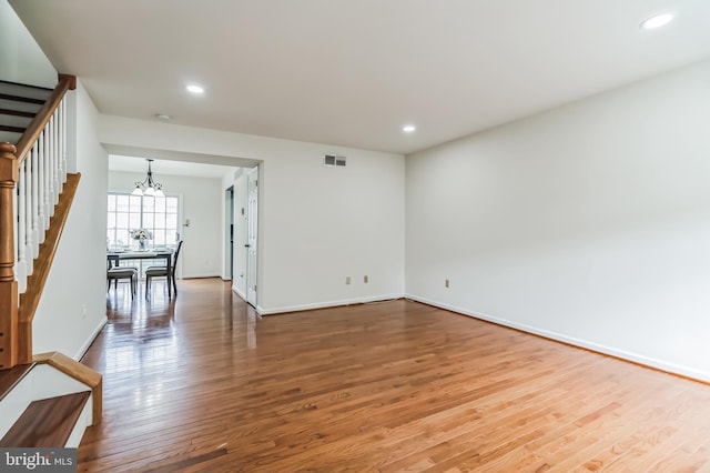 spare room with hardwood / wood-style flooring and an inviting chandelier