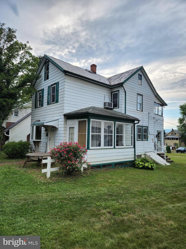 back of house featuring central air condition unit and a lawn