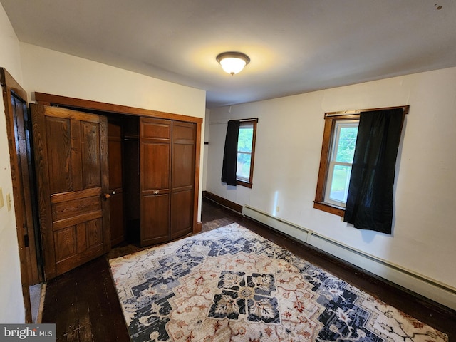 unfurnished bedroom featuring a closet, dark wood-type flooring, and a baseboard radiator