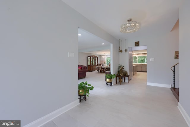 hallway featuring light tile patterned flooring and a notable chandelier