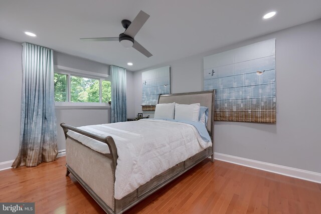 bedroom with a baseboard radiator, hardwood / wood-style flooring, and ceiling fan