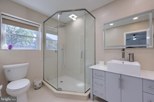 bathroom featuring vanity, tile patterned floors, tile walls, a shower with shower door, and toilet