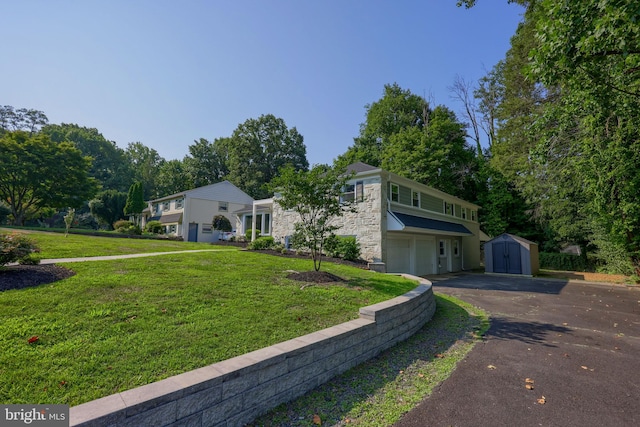 view of front of property featuring a storage unit, a garage, and a front lawn