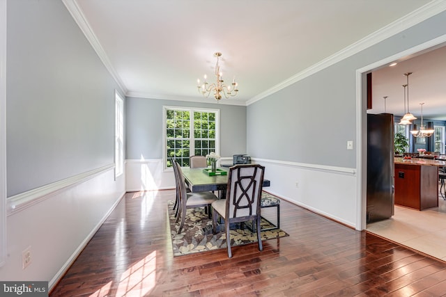 dining space with dark hardwood / wood-style flooring, crown molding, and a chandelier