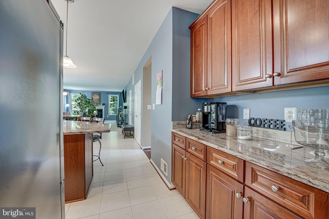 kitchen featuring a breakfast bar, decorative light fixtures, light stone countertops, and light tile patterned floors