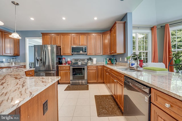 kitchen featuring light stone counters, stainless steel appliances, sink, and hanging light fixtures