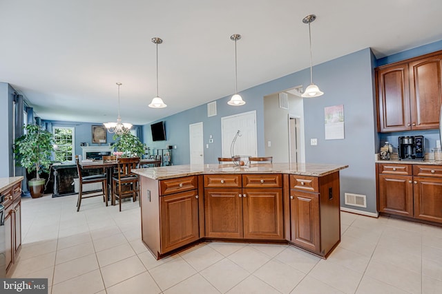 kitchen featuring light stone countertops, a center island, pendant lighting, and light tile patterned floors