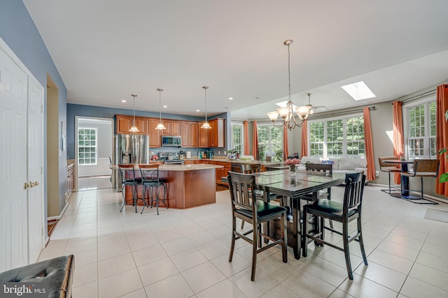 tiled dining room with a skylight and a chandelier