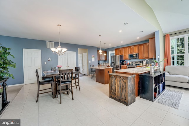 kitchen featuring an inviting chandelier, hanging light fixtures, stainless steel appliances, a center island, and kitchen peninsula