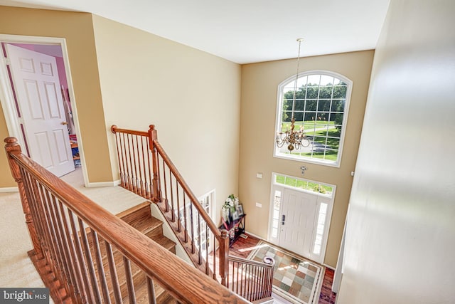 carpeted foyer entrance featuring a notable chandelier