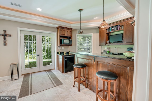 kitchen featuring sink, dark stone countertops, a kitchen breakfast bar, decorative light fixtures, and french doors