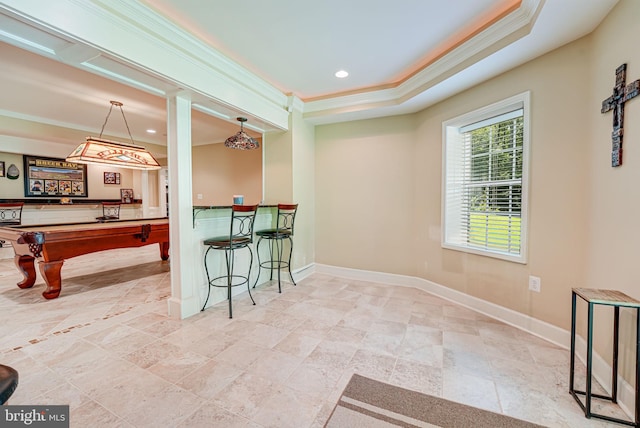 interior space featuring billiards, a breakfast bar area, hanging light fixtures, ornamental molding, and a raised ceiling