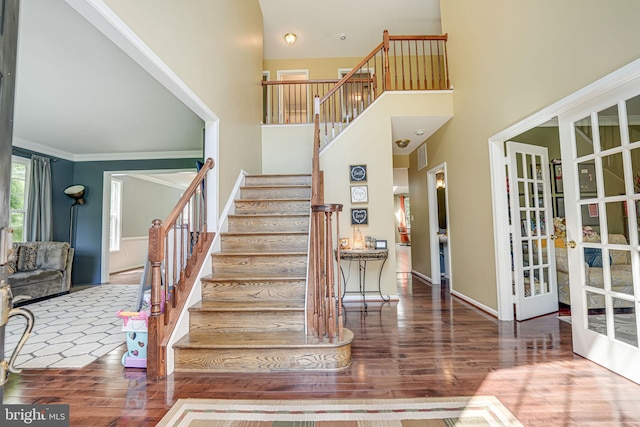 stairway featuring crown molding, a towering ceiling, hardwood / wood-style floors, and french doors