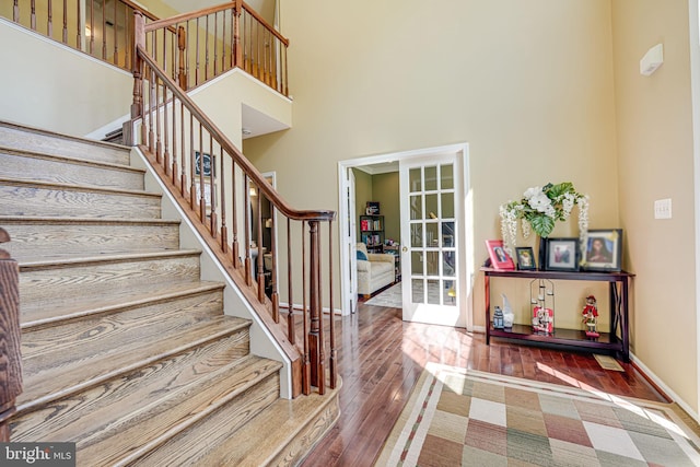 foyer entrance with hardwood / wood-style flooring, a towering ceiling, and french doors