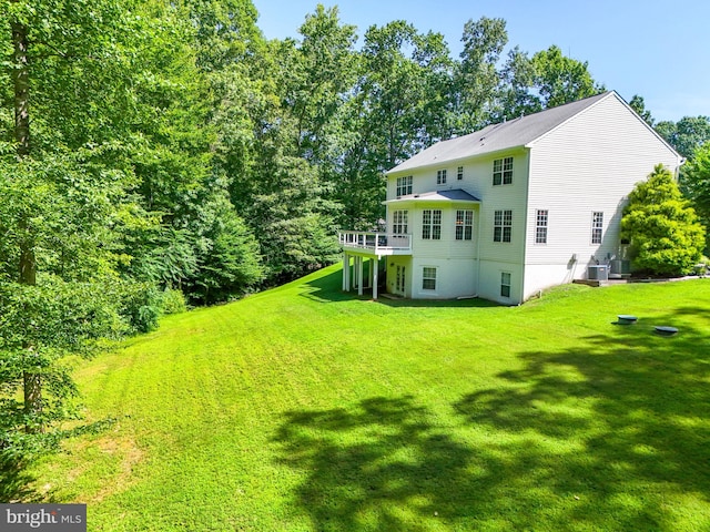 rear view of house featuring a wooden deck and a yard