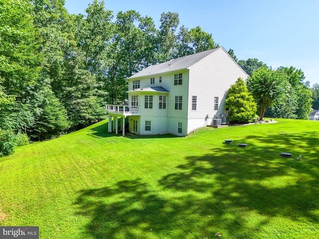 rear view of property featuring a wooden deck, central AC, and a lawn