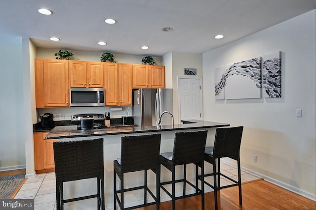 kitchen with a kitchen island with sink, a breakfast bar area, stainless steel appliances, and recessed lighting