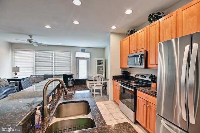 kitchen featuring light tile patterned floors, appliances with stainless steel finishes, dark stone countertops, a sink, and recessed lighting