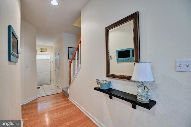 corridor with baseboards, stairway, recessed lighting, and light wood-style floors