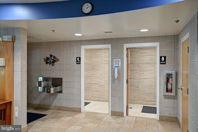 bathroom featuring recessed lighting, visible vents, and tile walls