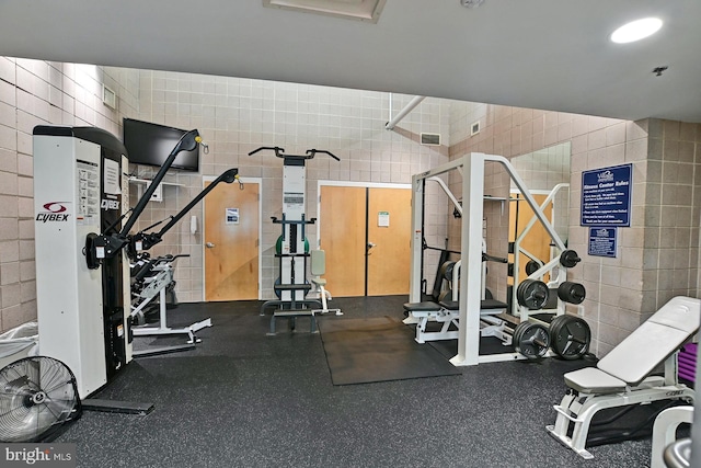 gym featuring visible vents and tile walls