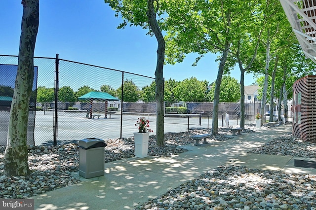 view of home's community with a tennis court and fence