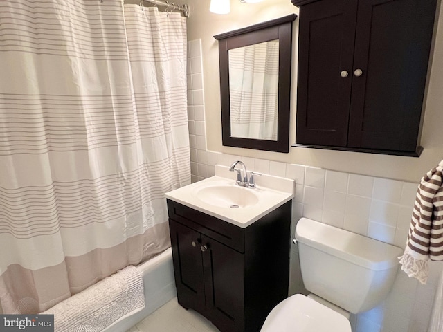 bathroom with shower / tub combo, toilet, tile walls, and vanity