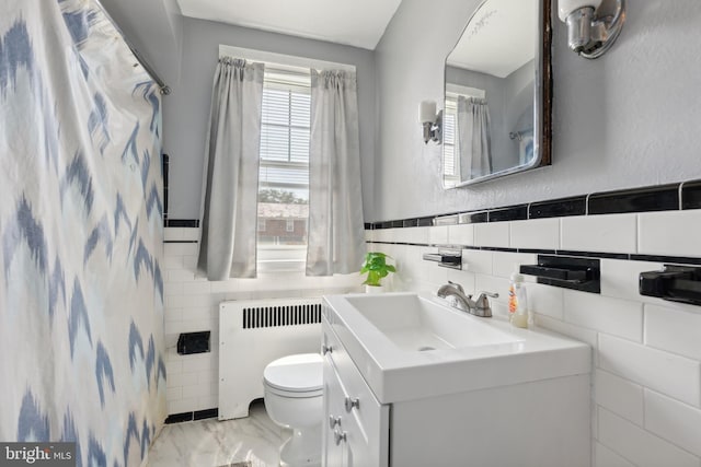 bathroom with vanity, toilet, radiator, and tile walls