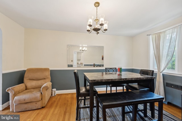 dining room featuring radiator, an inviting chandelier, and light hardwood / wood-style floors