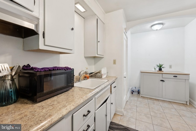 kitchen featuring sink, light tile patterned floors, and white cabinets