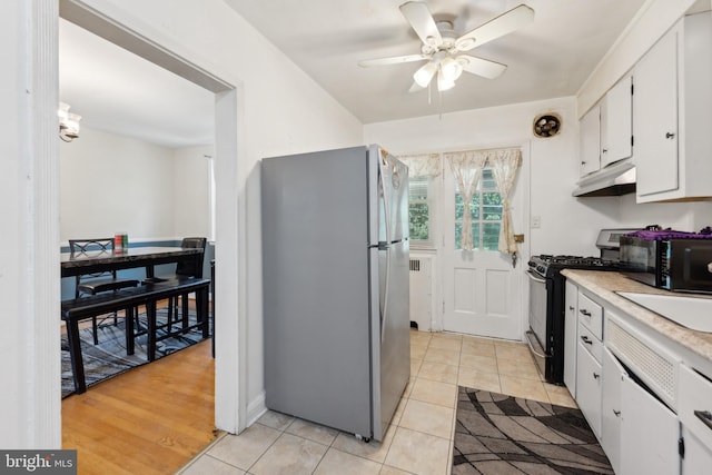 kitchen featuring ceiling fan, stainless steel appliances, light tile patterned floors, and white cabinets