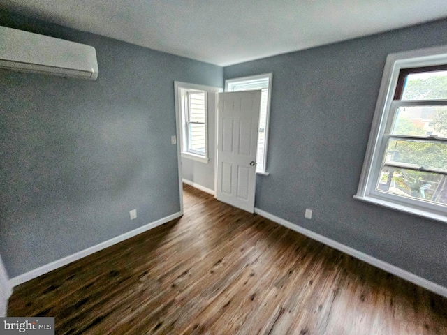 empty room with a wall mounted AC and hardwood / wood-style flooring