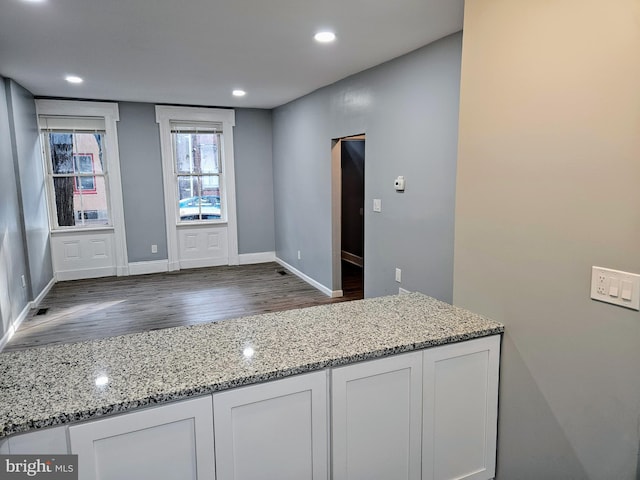 kitchen featuring white cabinetry, hardwood / wood-style flooring, and light stone countertops