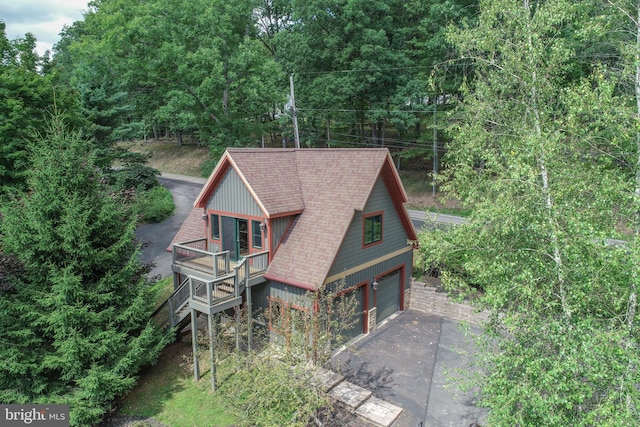 view of front facade featuring a garage, a shingled roof, driveway, stairway, and a wooden deck