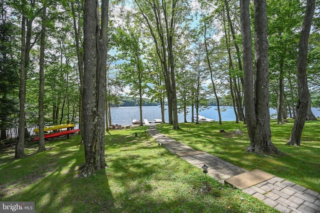 surrounding community with a water view and a lawn