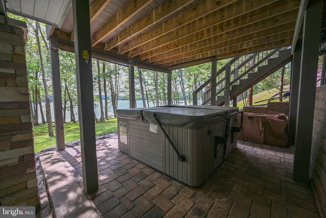 view of patio / terrace featuring a water view, a hot tub, and stairs