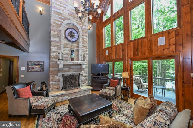 living room featuring a stone fireplace, plenty of natural light, wood finished floors, and wooden walls