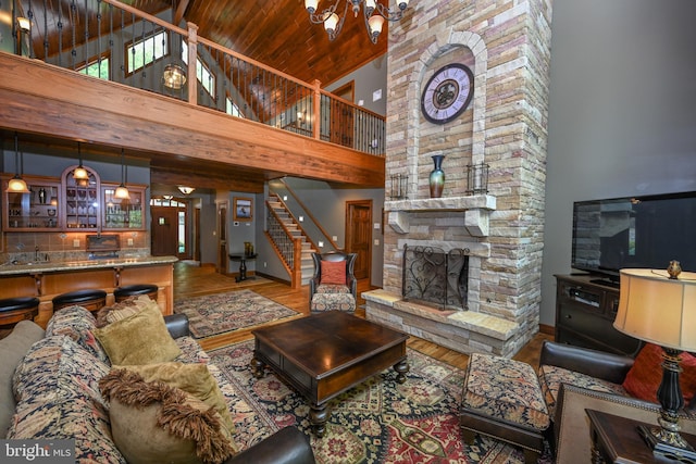 living room with stairs, a fireplace, wood finished floors, and a notable chandelier