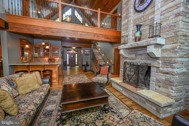 living room featuring a towering ceiling, a fireplace, stairway, and wood finished floors