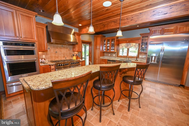 kitchen featuring glass insert cabinets, appliances with stainless steel finishes, a kitchen island, wooden ceiling, and wall chimney exhaust hood