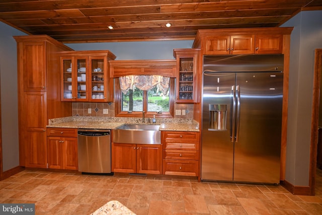 kitchen with appliances with stainless steel finishes, decorative backsplash, sink, light stone countertops, and light tile patterned flooring